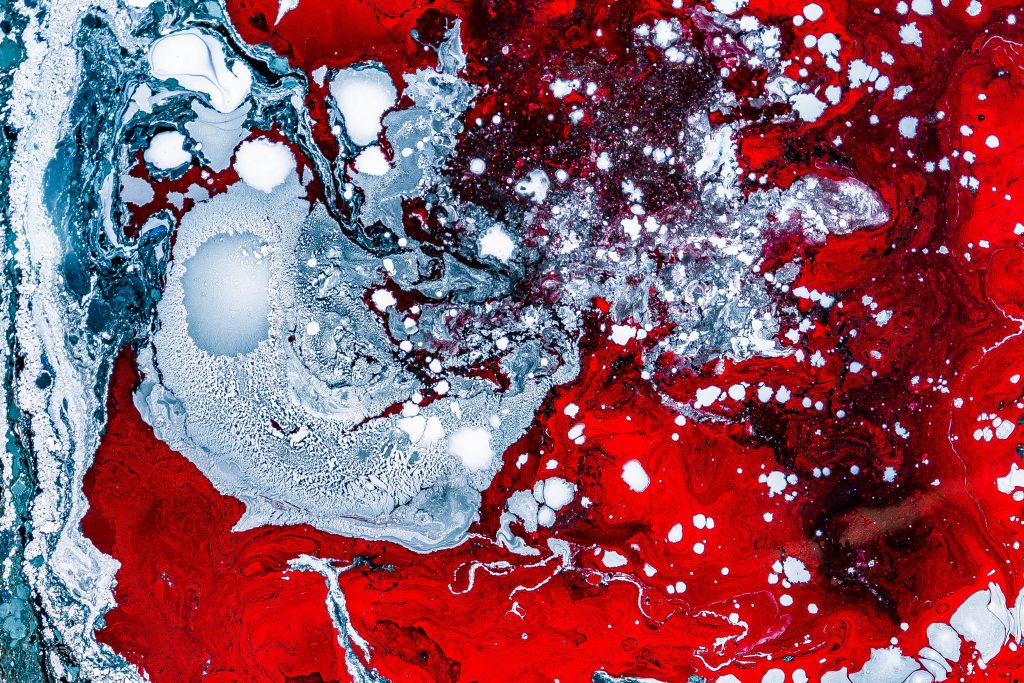 Abstract of two liquids, one blood red, one clear, colliding.